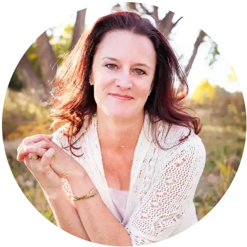 A woman wearing glasses and a green coat holds a white paper