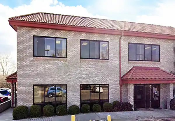  Individual at a table using a notebook , with a laptop placed next to them