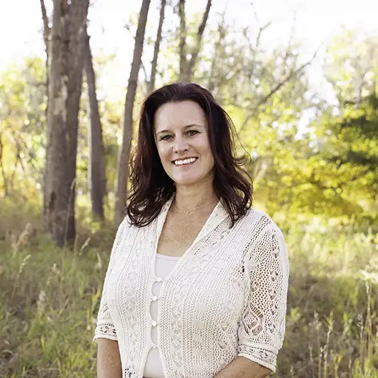 A woman in glasses and a coat stands confidently